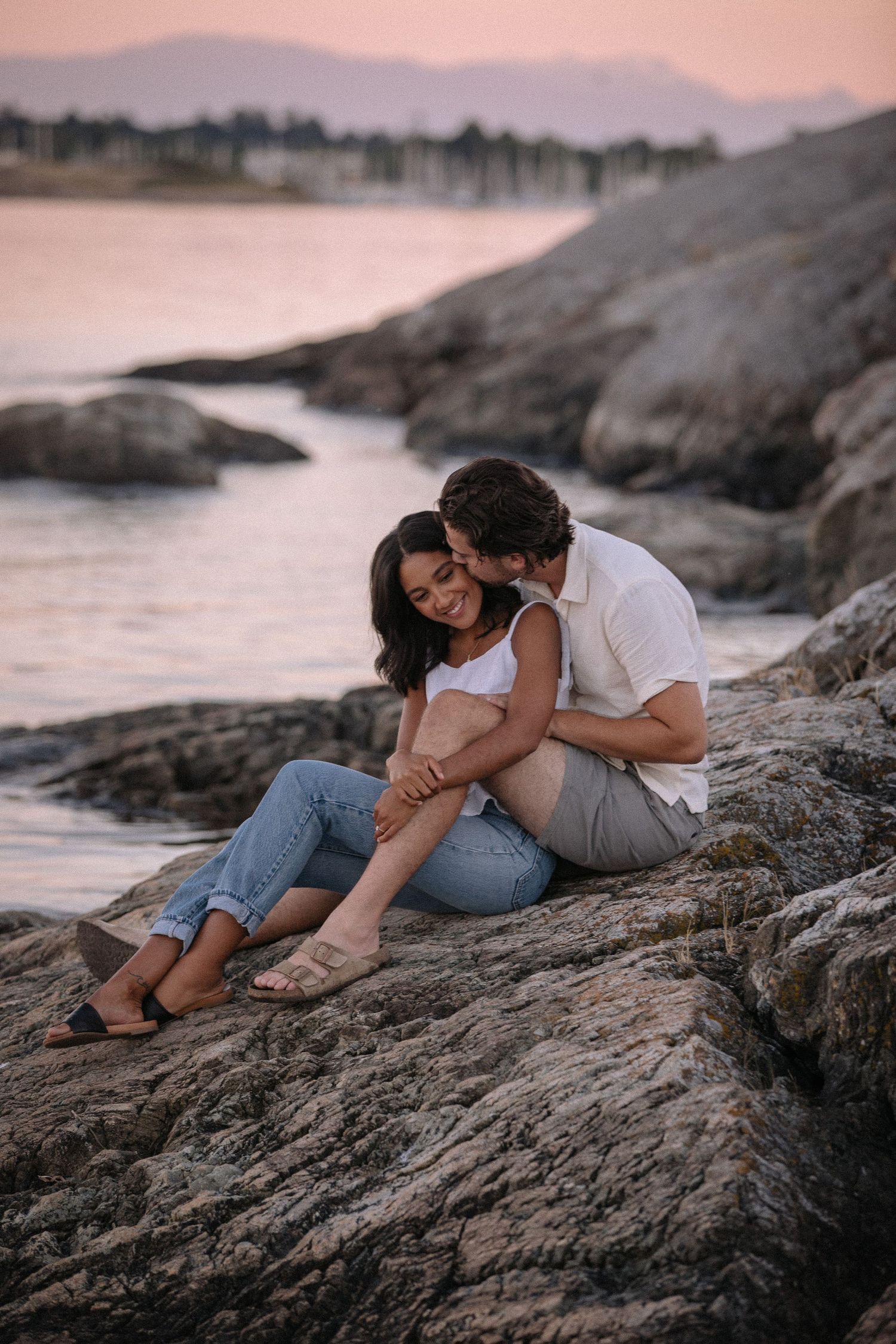 Couple sitting on rocks during a pink sunset