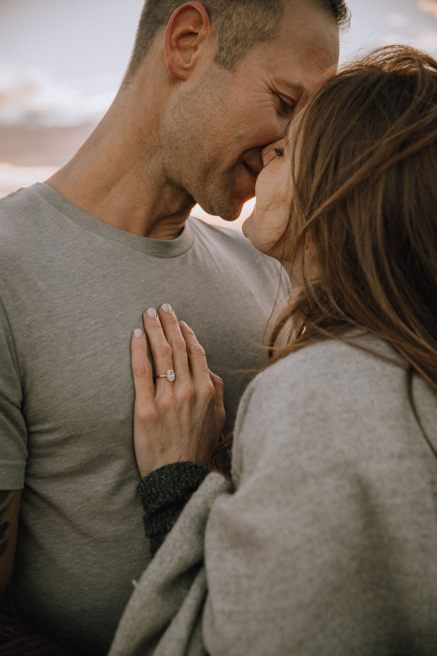 Couple kissing with engagement ring on his chest