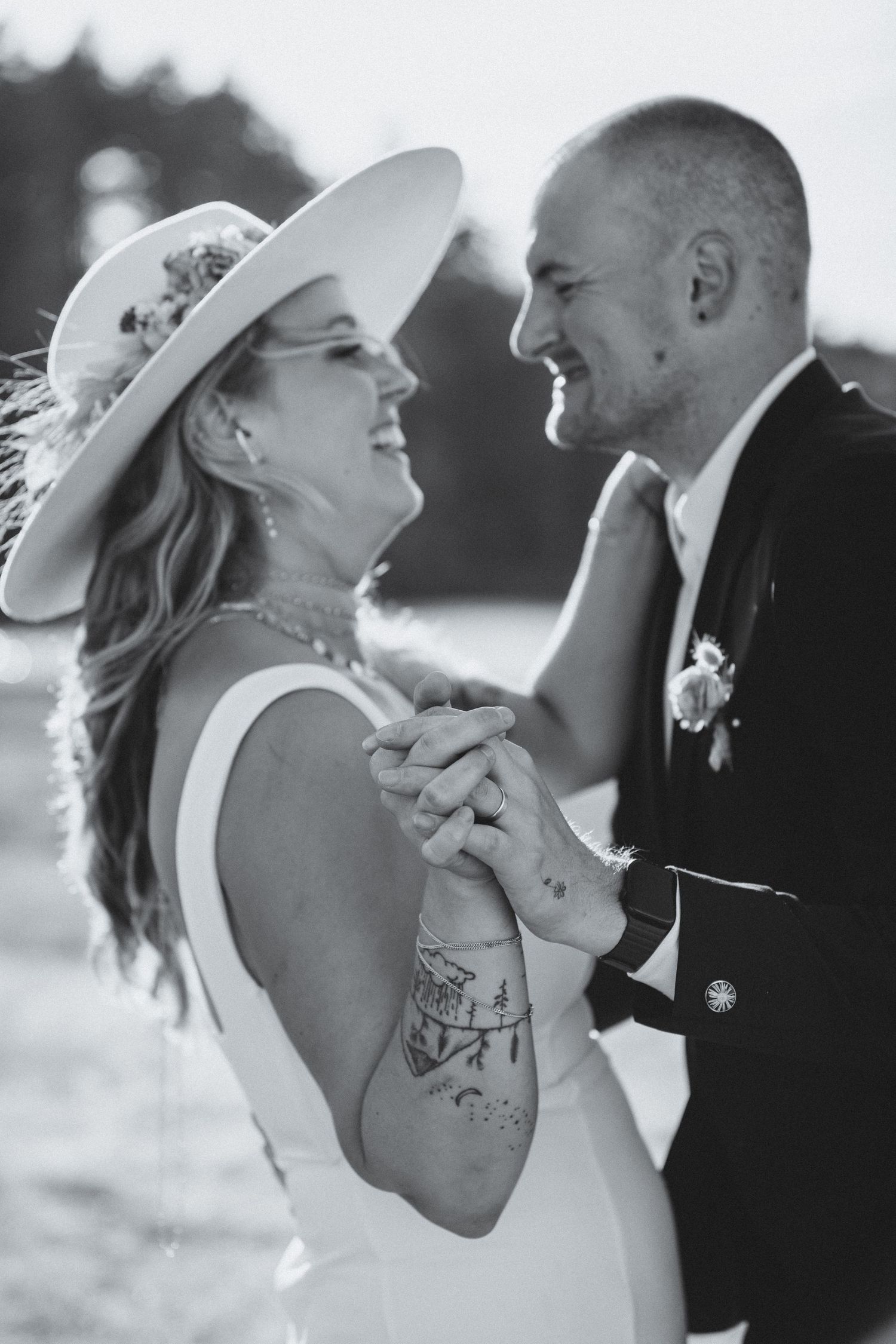 Bride and groom smiling at each other and holding hands and showing wedding rings
