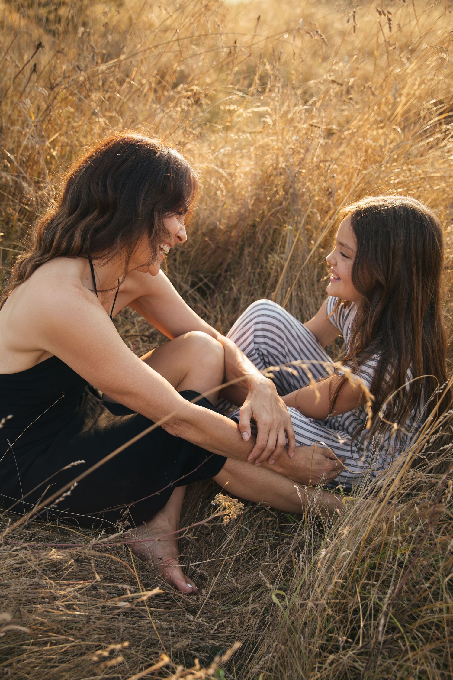 Mother and daughter laughing together in a golden field