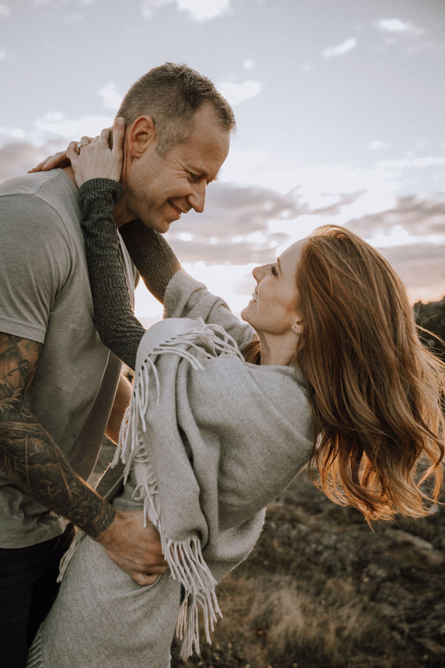 Women leaning back smiling while holding on to boyfriends neck