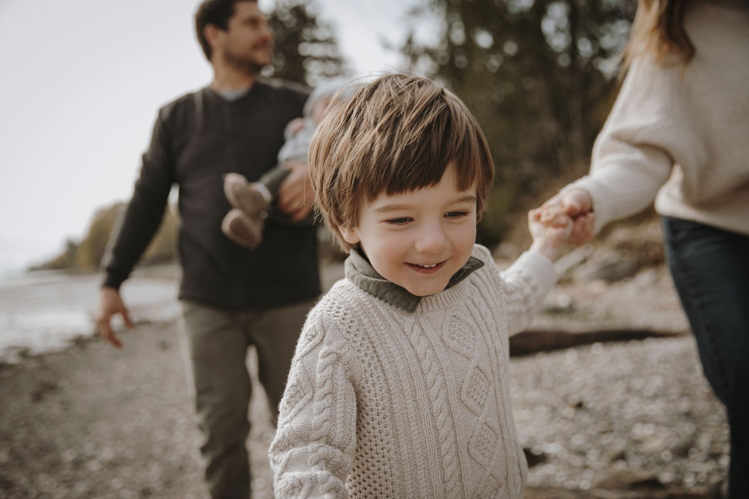 Close up of boy running towards photographer while holding mom's hand