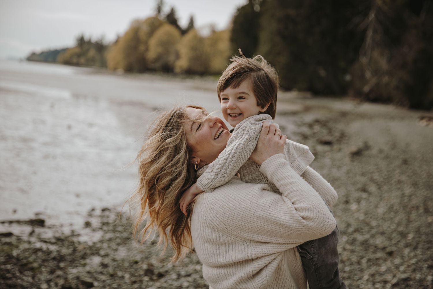 Mom holds up young son in a big hug on the beach