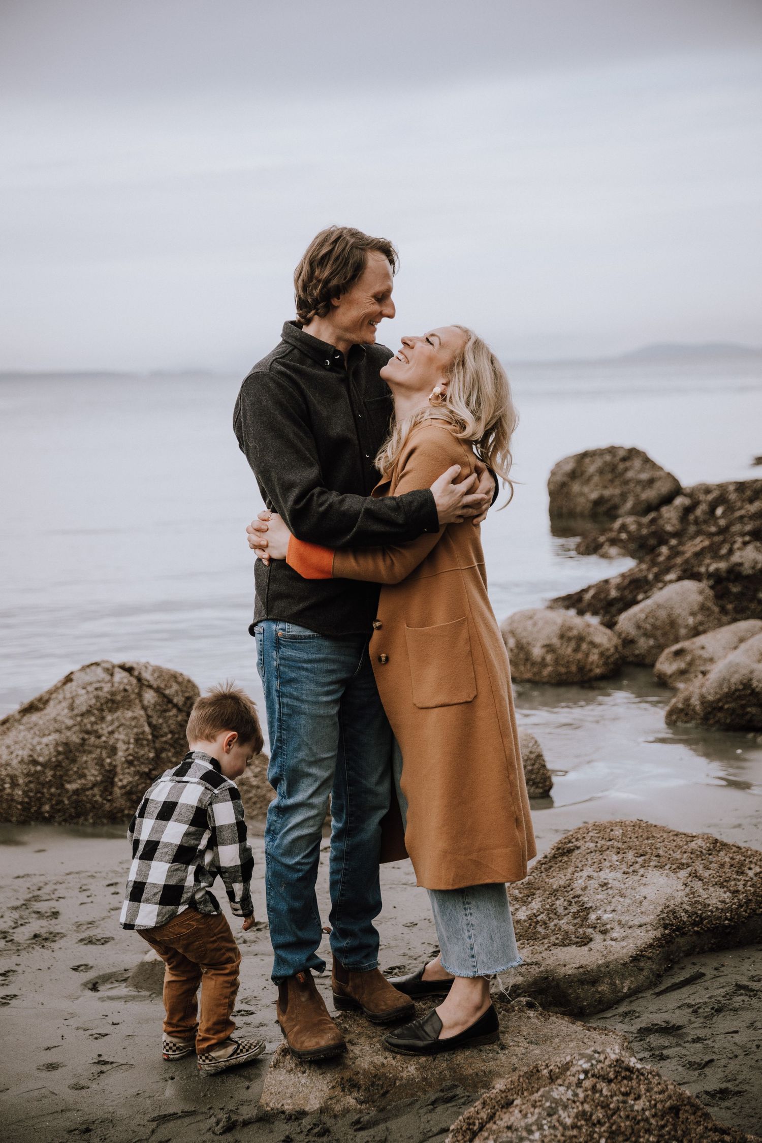 Son runs around mom and dad while they hug and smile at each other