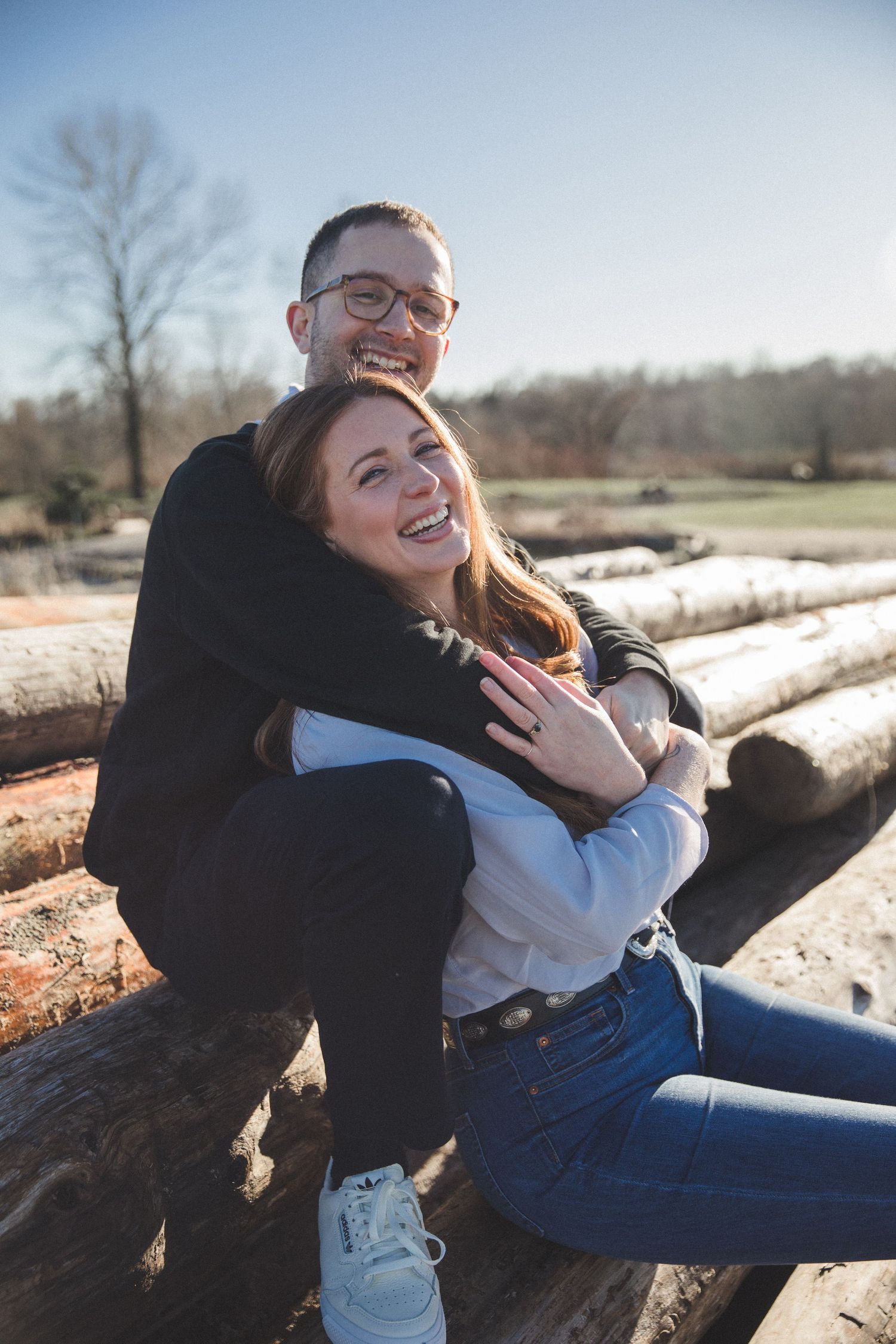 Couple cuddling and smiling while sitting on logs