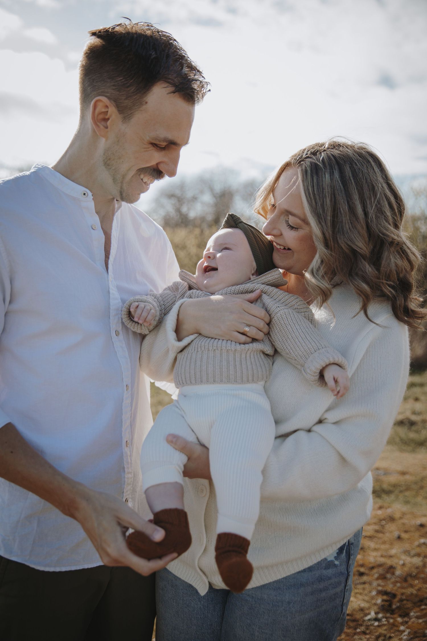 Baby girl smiling up at dad while mom holds her