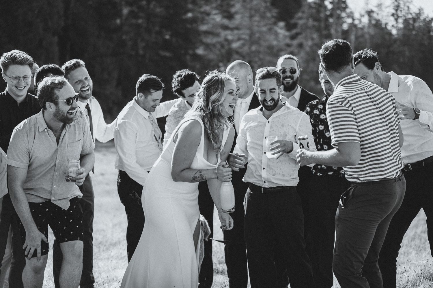 Bride laughing surrounded by groomsmen after champagne shower