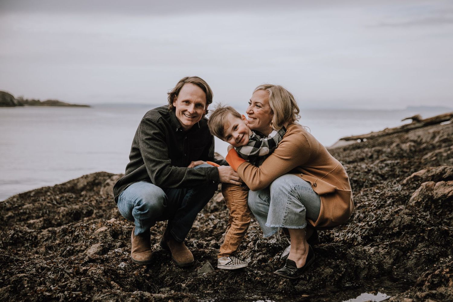 Boy hugs mom on the beach while everyone smiles