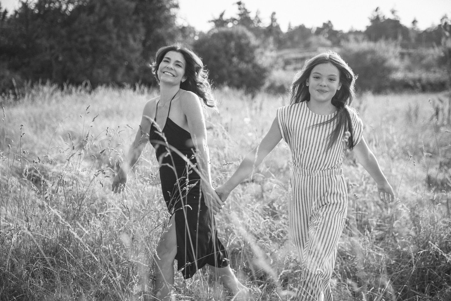 Mother and daughter running through a grass field
