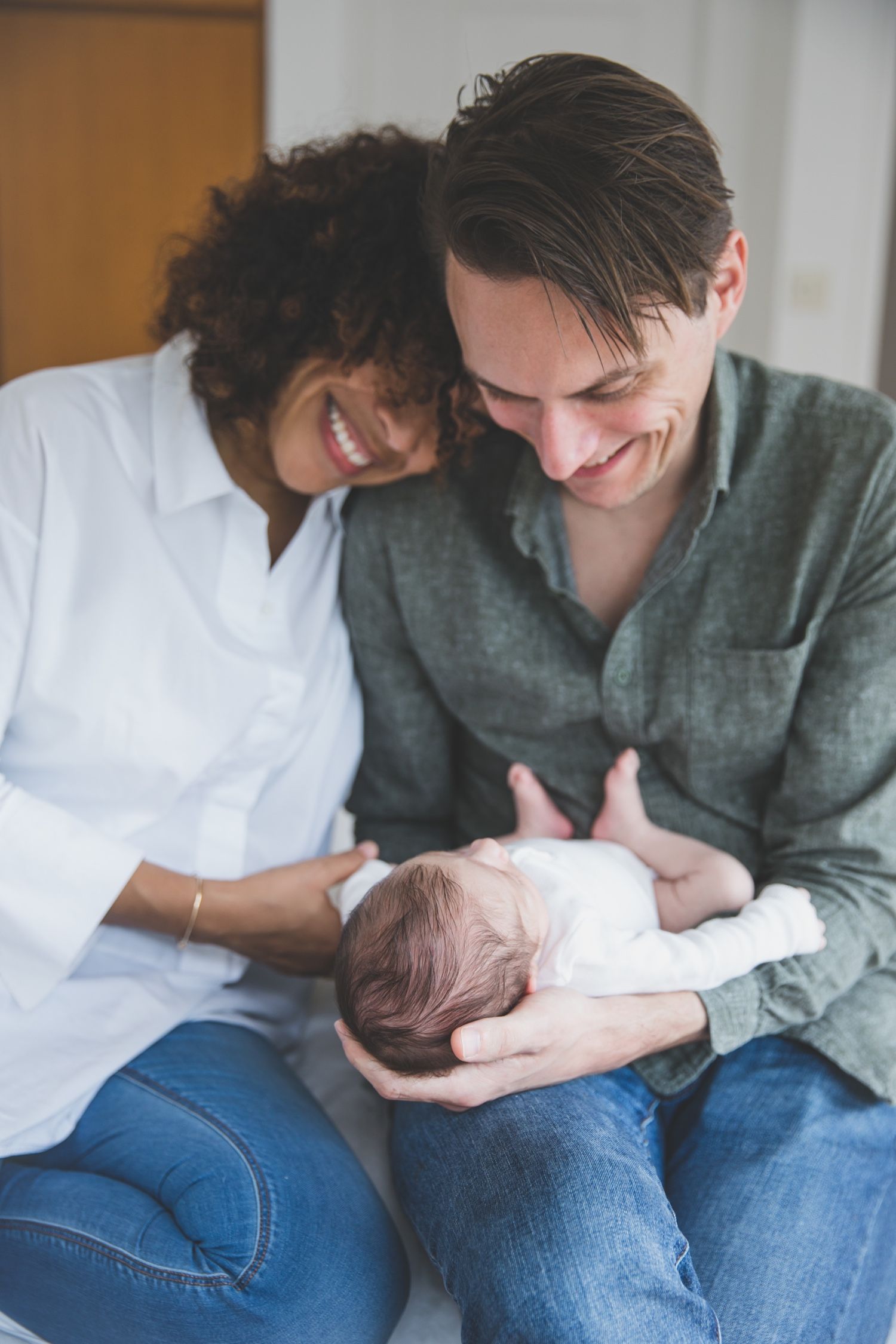 Mom and dad look down lovingly at newborn baby