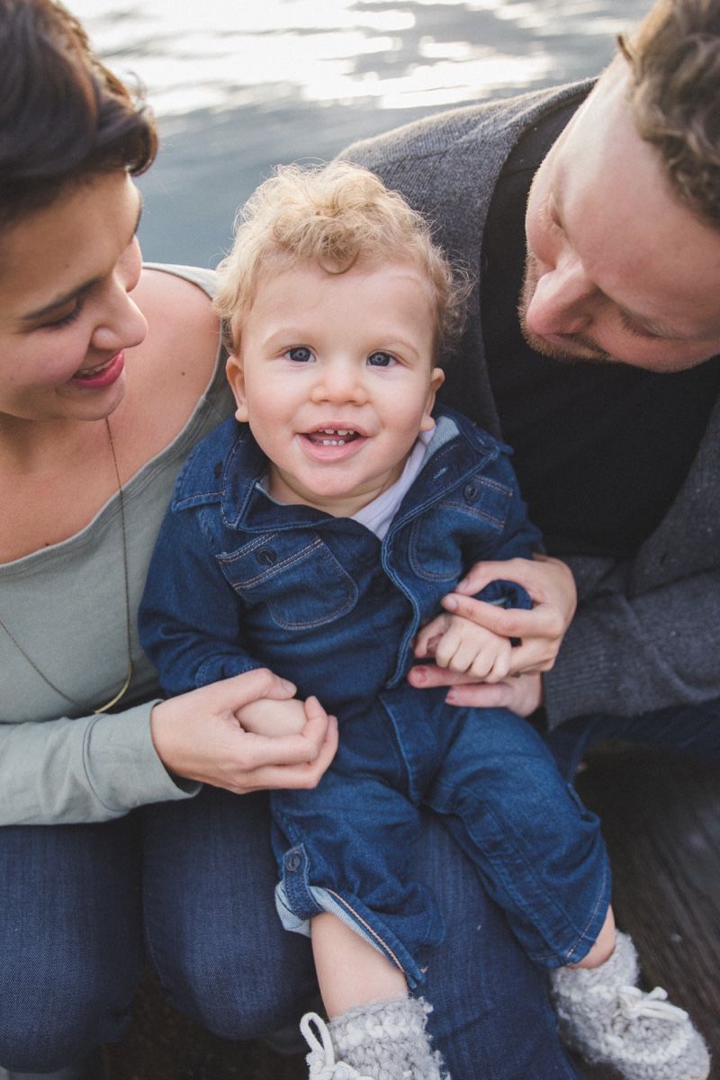Little boy smiling up at photographer while mom and dad smile at him