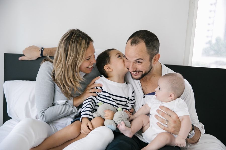 Family cuddles and kisses on their bed