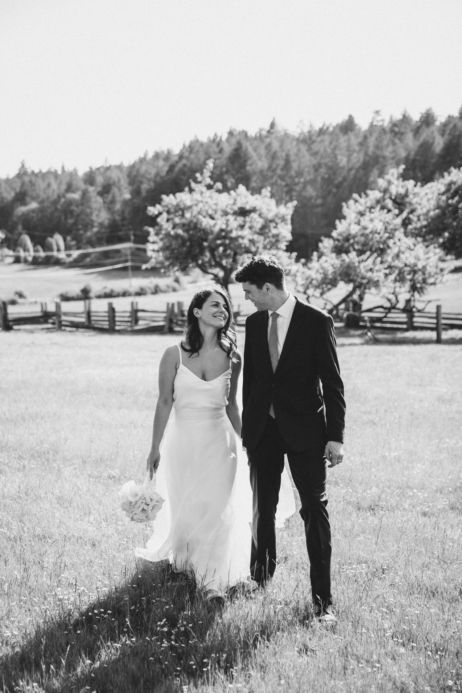 Bride and groom look at each other lovingly while walking towards the photographer