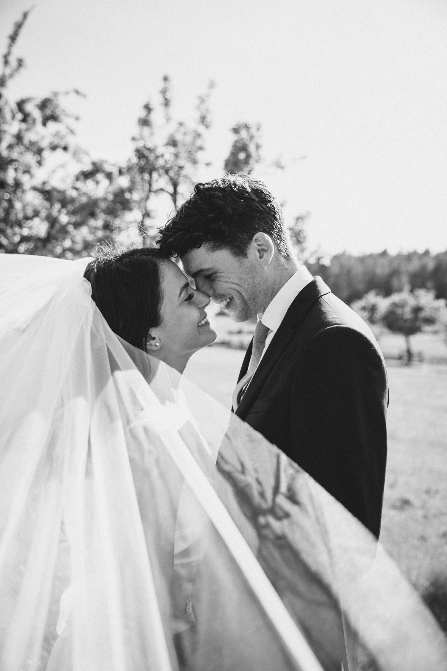 Veil flies toward photographer while bride and groom gaze into each other eyes