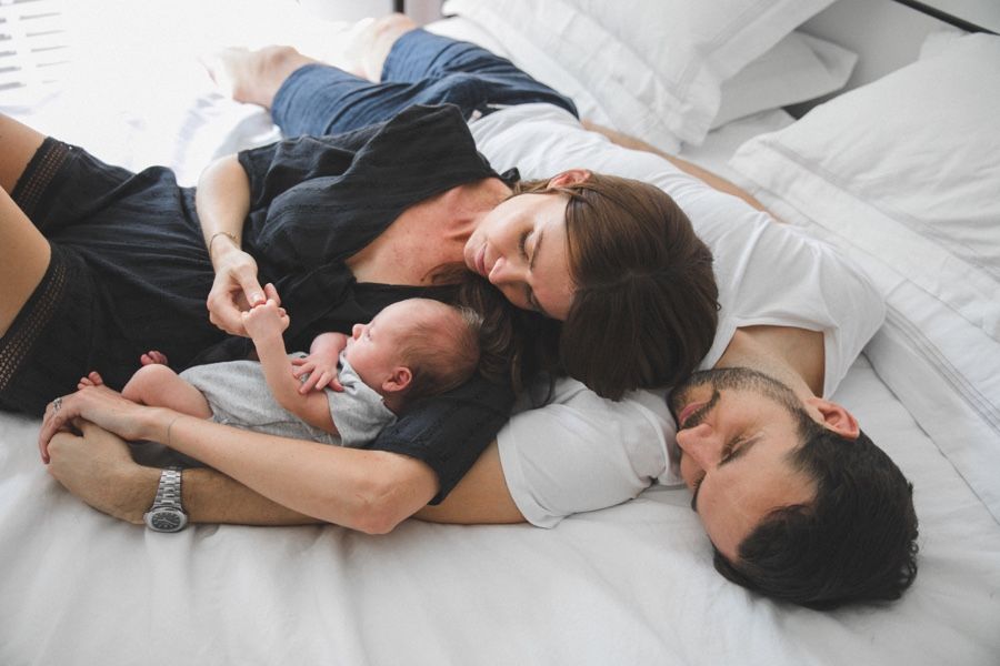 Family lie down on the bed with newborn baby