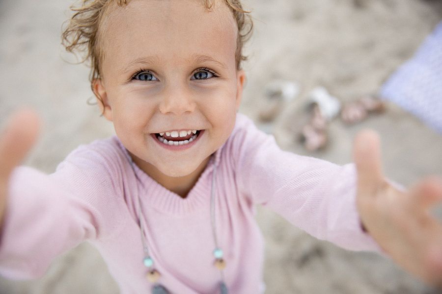 Little girl has a big smile while reaching up for the camera