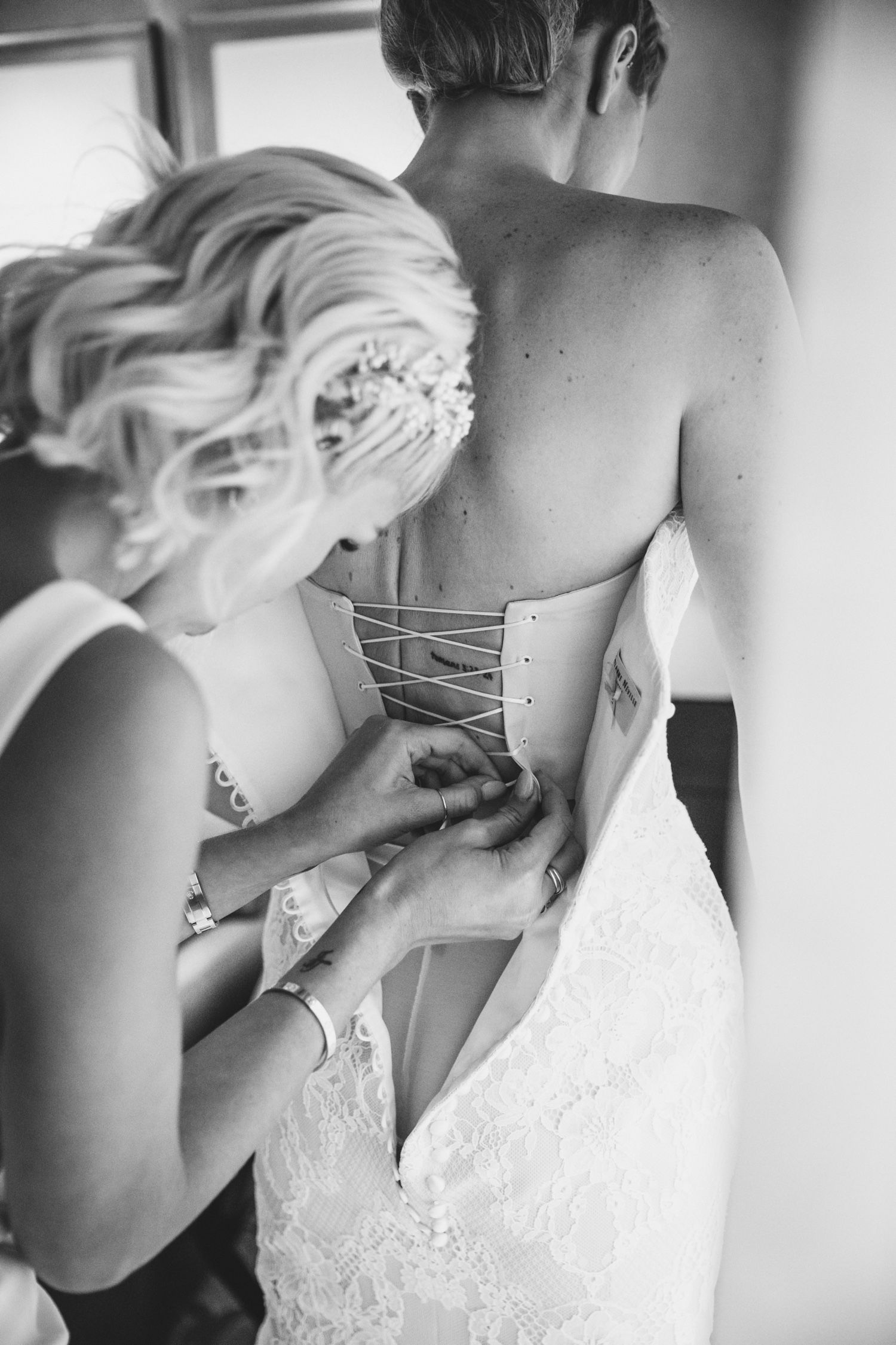 Bridesmaid helps bride get dressed