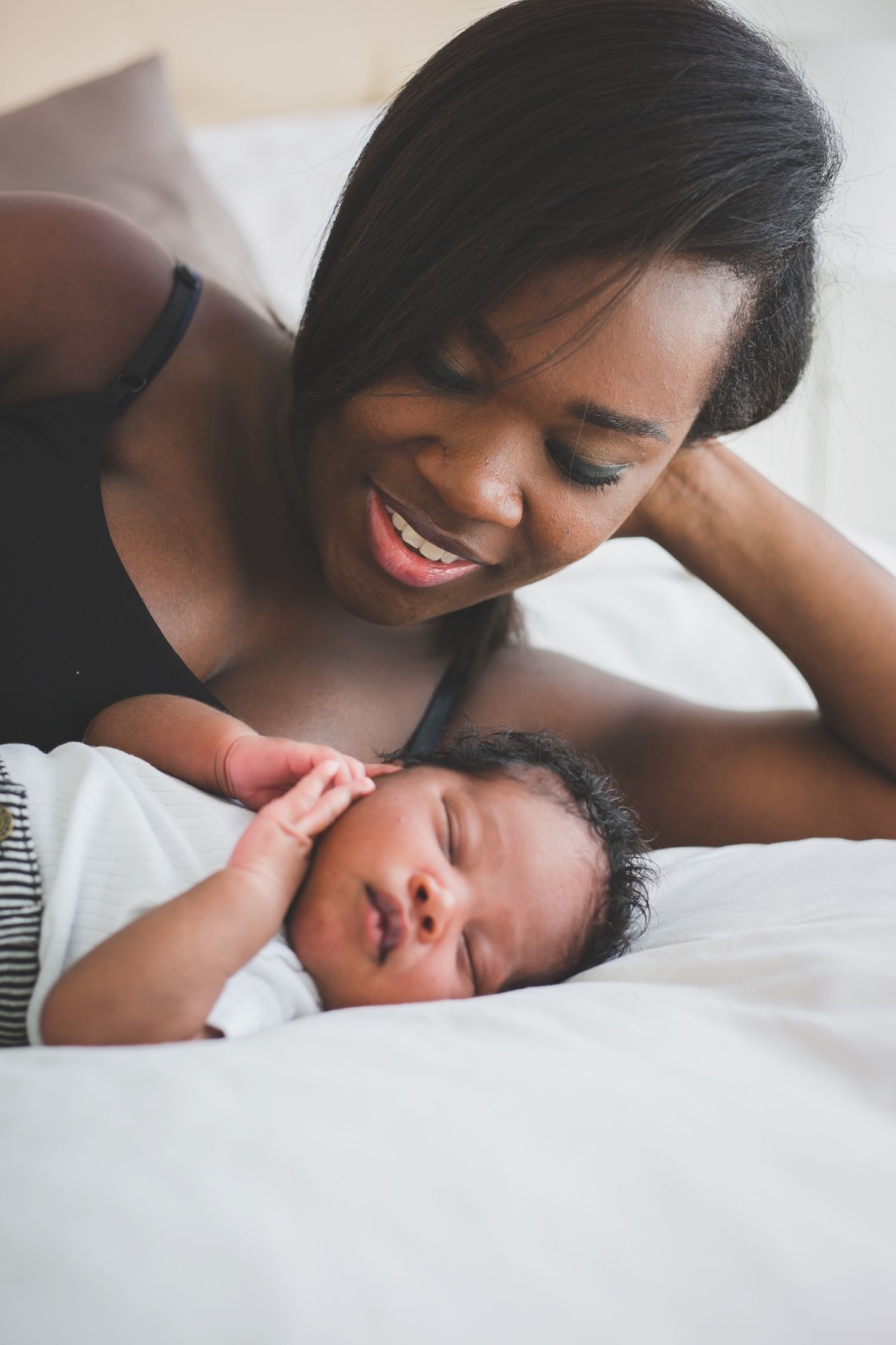 Mom smiling at sleeping newborn