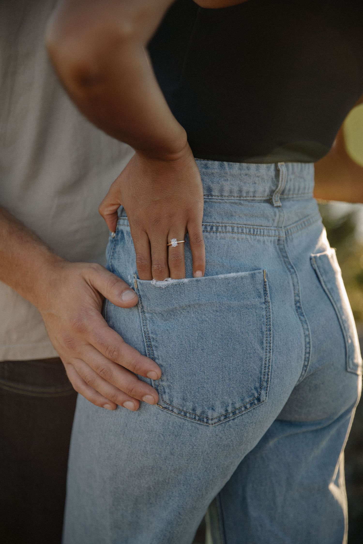 Girlfriend has engagement ring in back pocket while boyfriend holds her