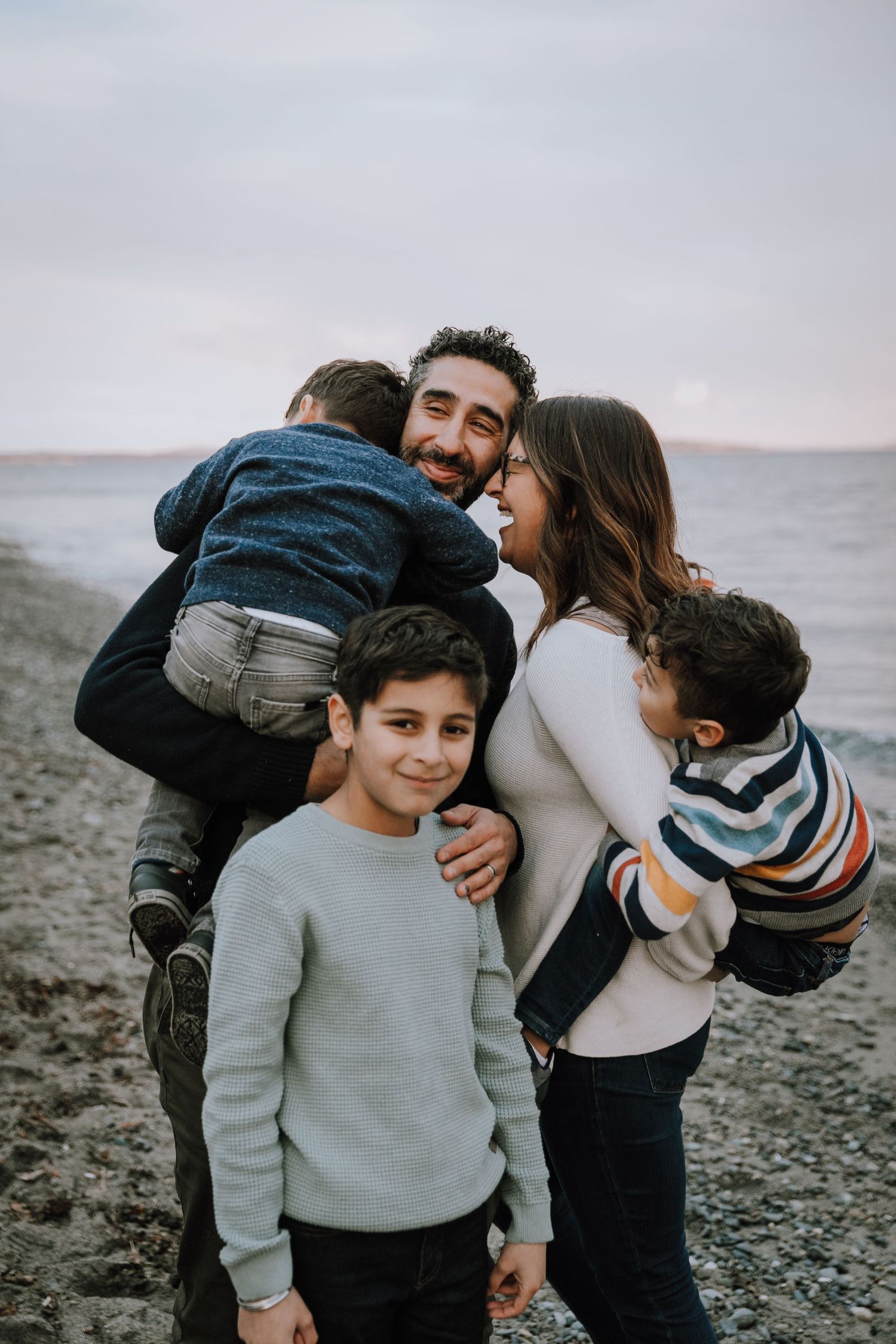 Mom and dad give their kids piggy back rides while laughing