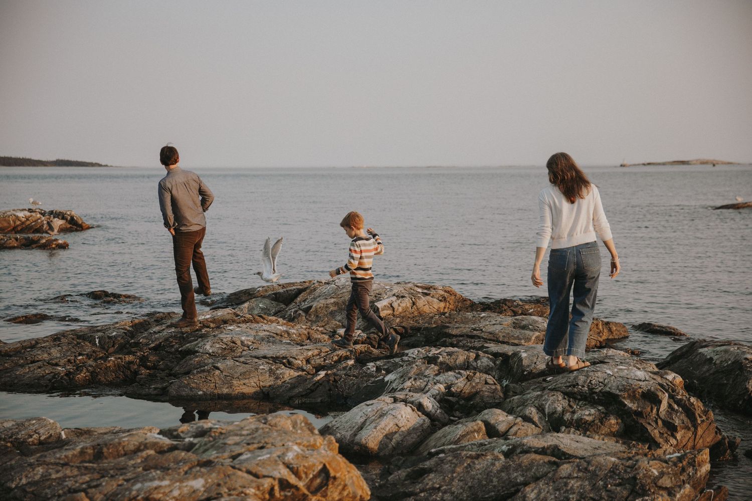 Family of three walking along the rocks by the ocean