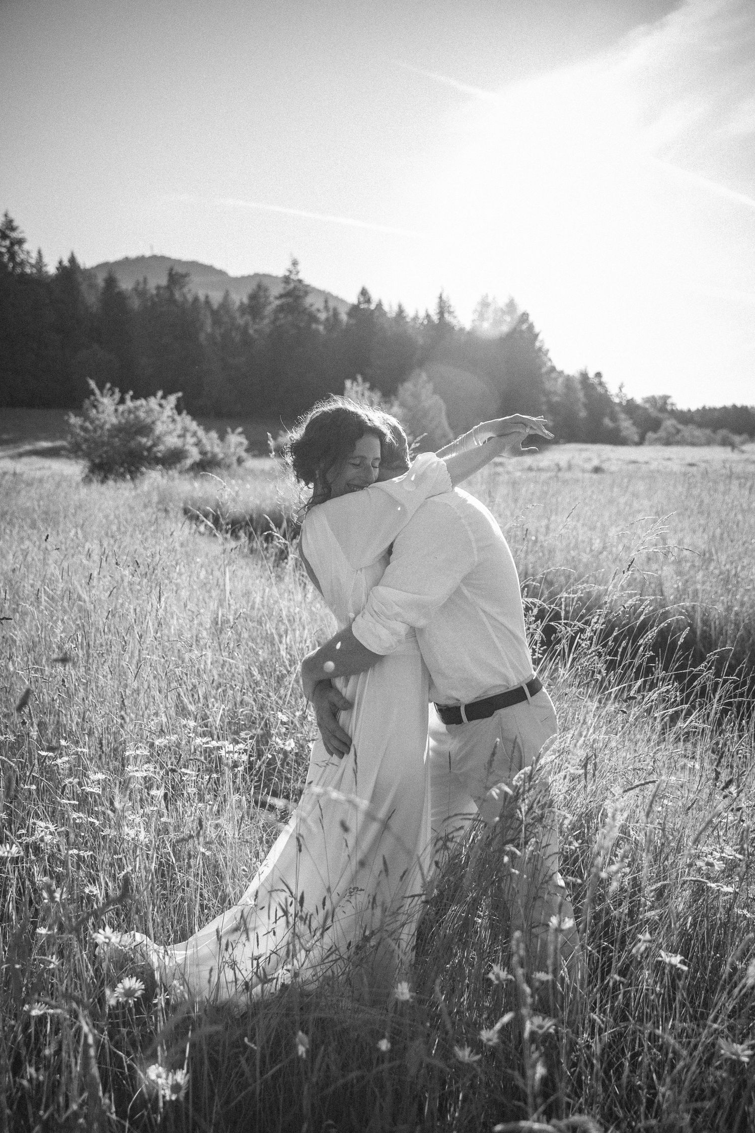 Wedding couple hugging in a field at sunset