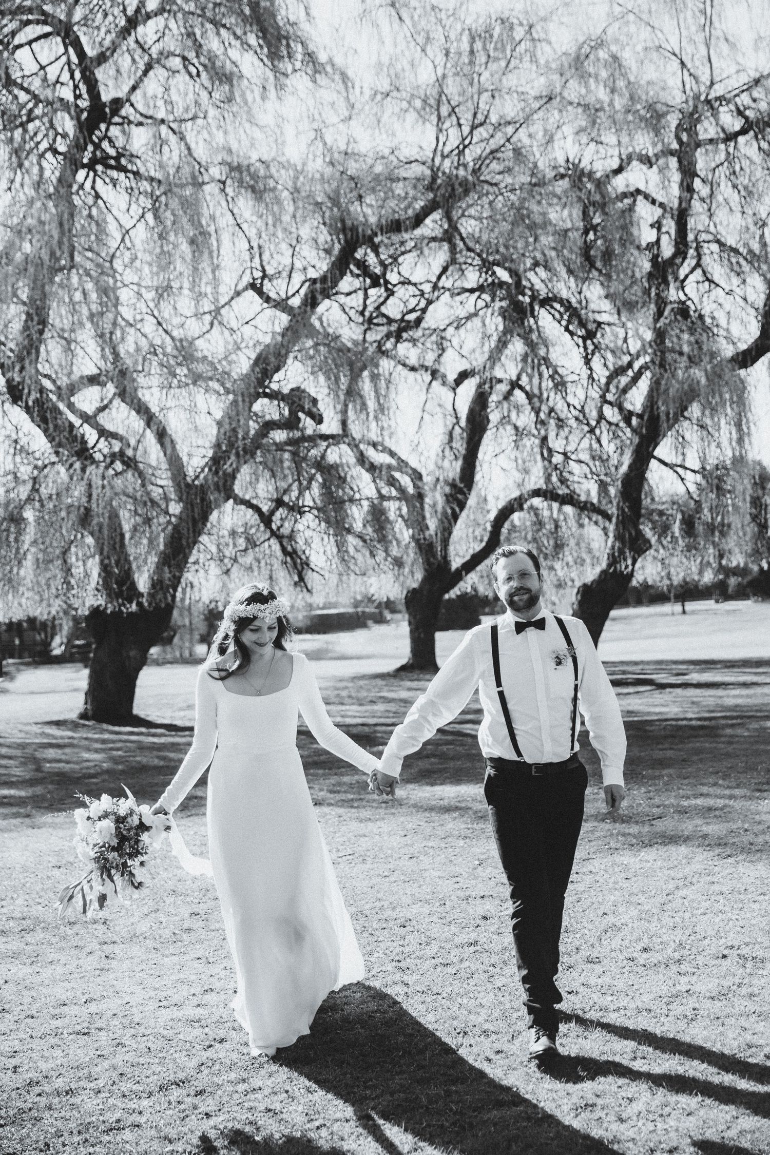 Bride and groom walk towards photographer with sunlight behind them
