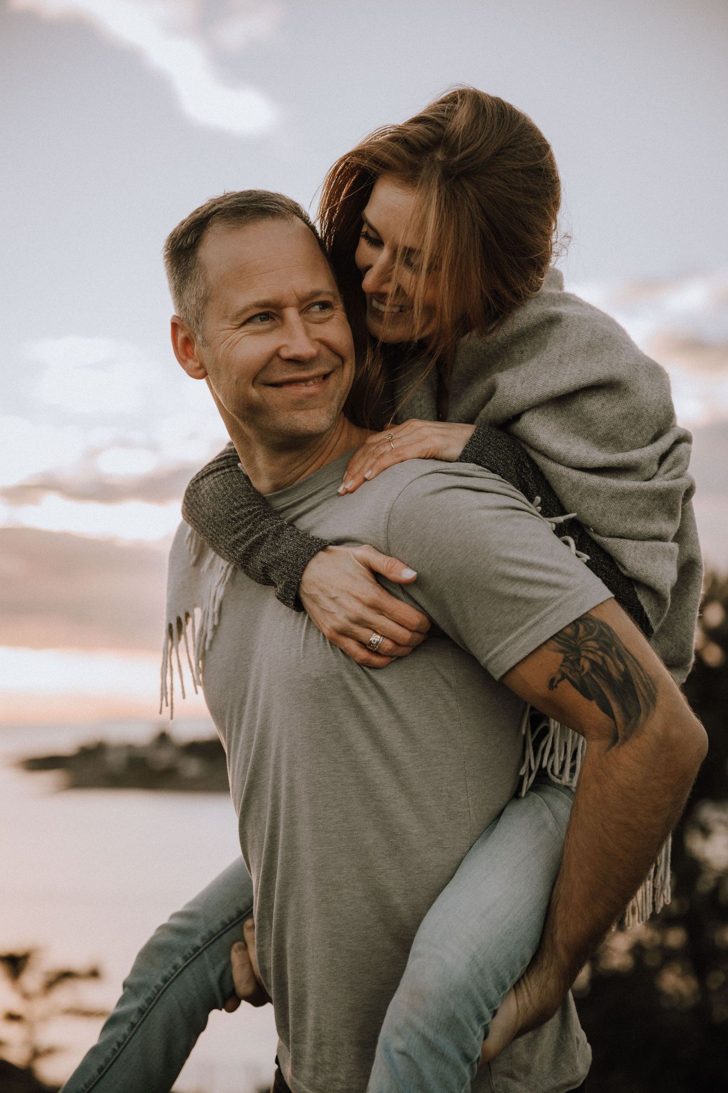 Engagement shoot, girlfriend smiling while getting a piggy back from her partner