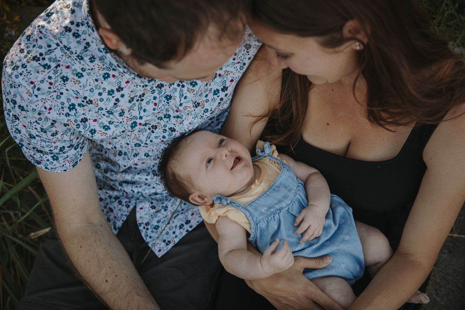 Mom and dad looking down at baby girl smiling at them