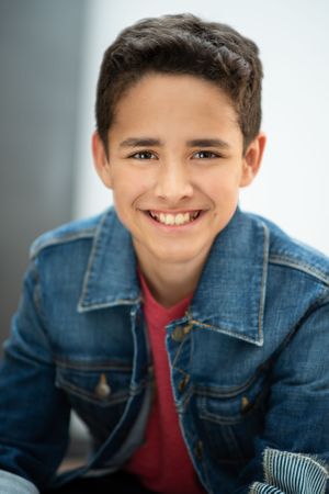 Studio portrait of youth wearing denim jacket and red shirt with natural smile.