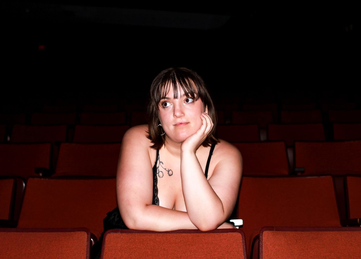 A person leans against theater seats and looks off camera during a portrait session