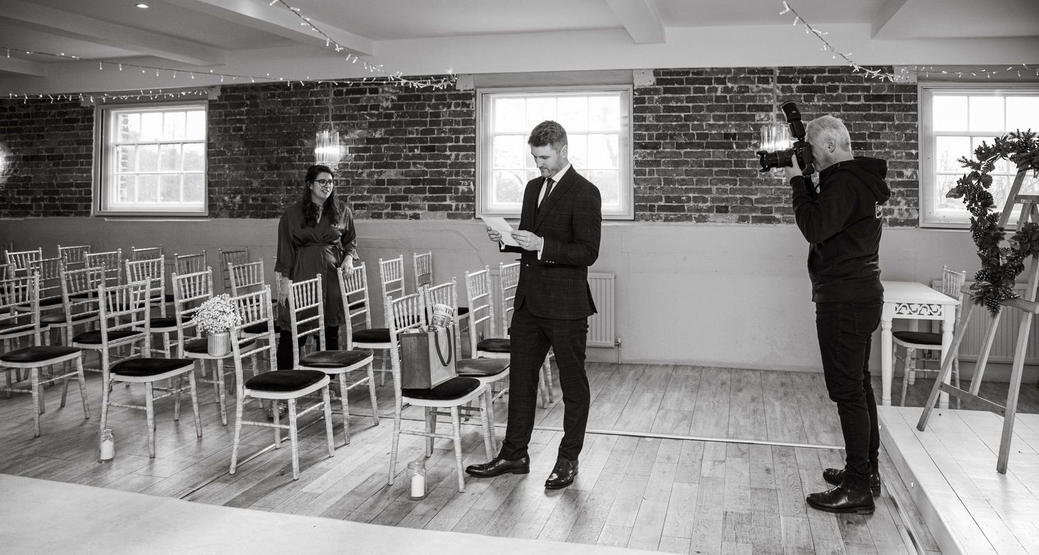 Empty indoor venue setup showing rows of white chairs in a brick-walled room.