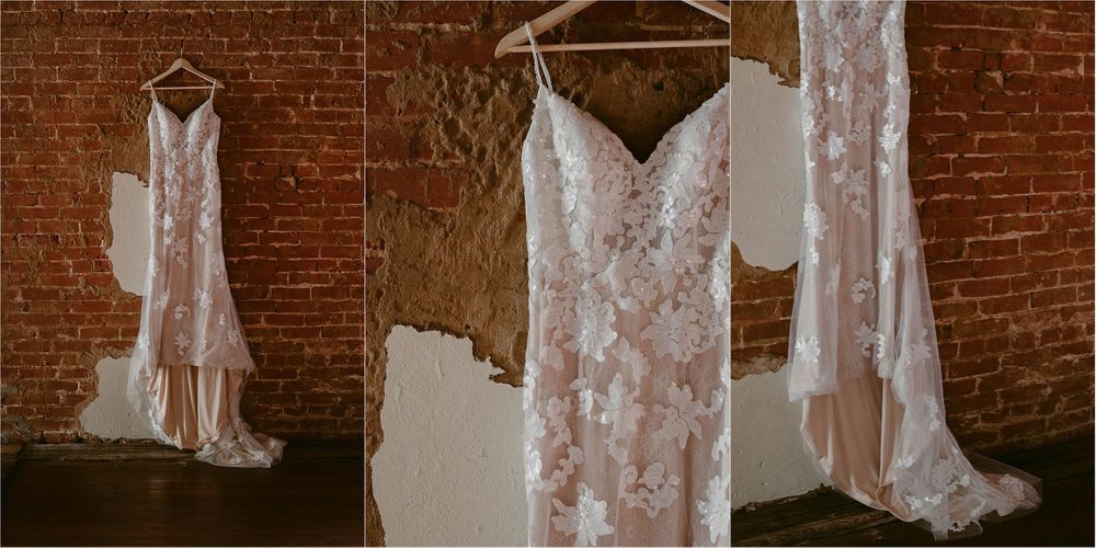 Collection of white lace wedding dresses hanging against exposed brick wall in vintage style.