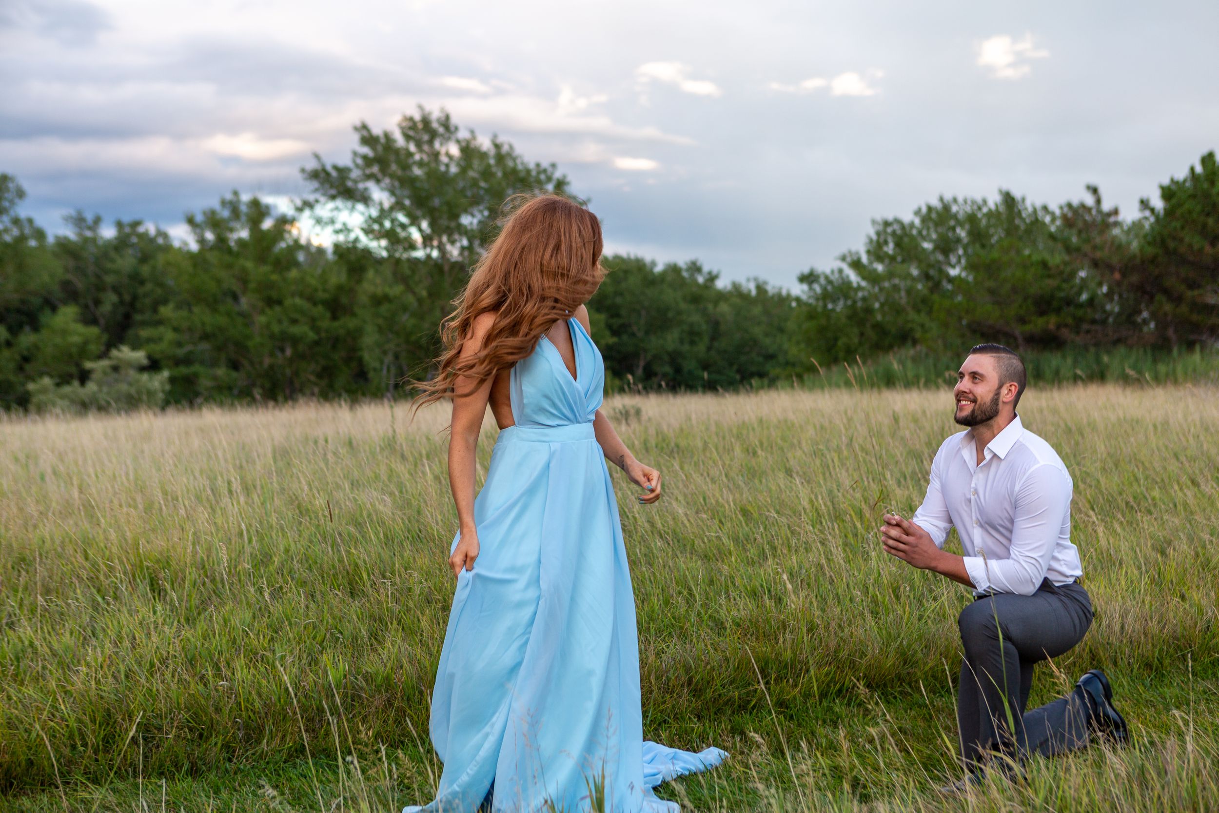 A proposal scene unfolds in a scenic meadow with dramatic storm clouds overhead.
