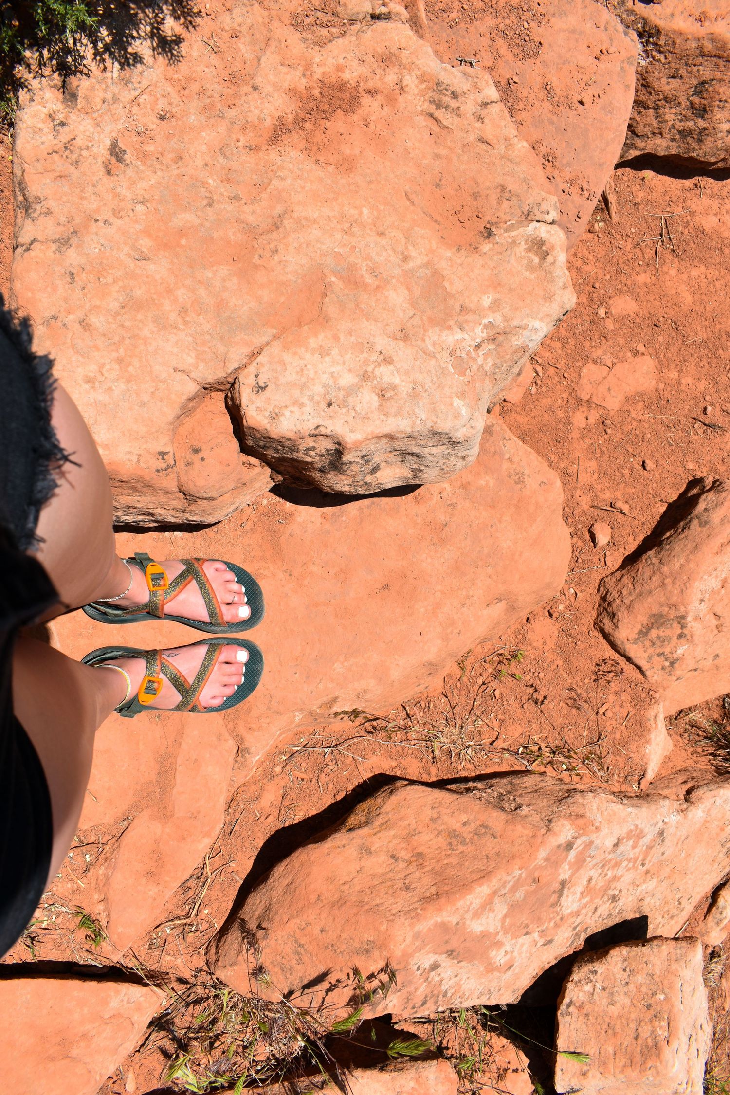 Colorful sandals resting on red sandstone rocks in the desert sun.