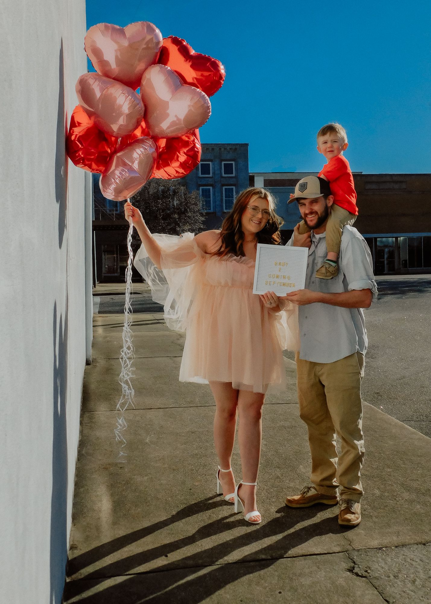 A couple celebrates their baby announcement session with Miranda Jo Photography in Rockingham, NC with balloons and a letterboard