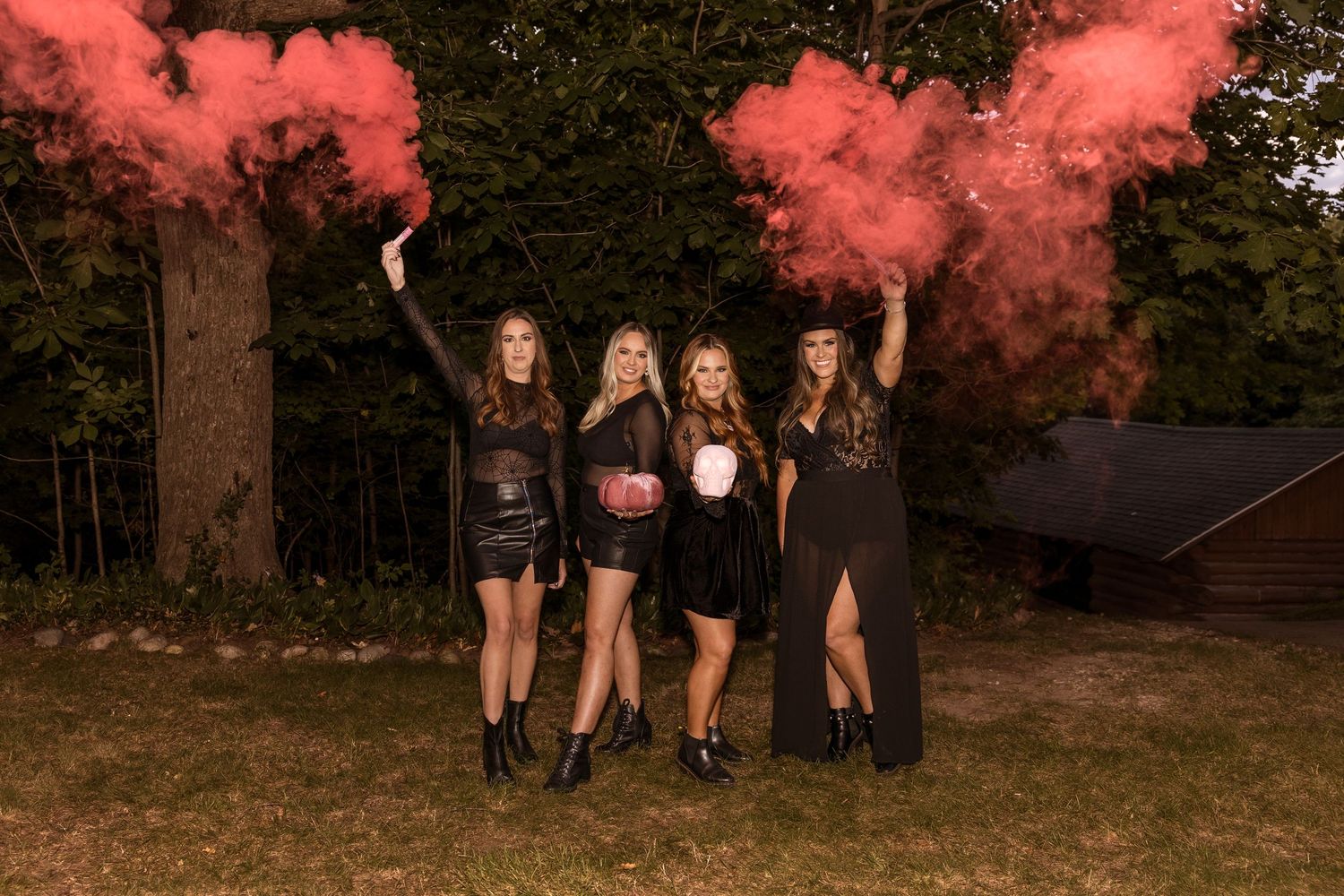 Group in black outfits poses with red smoke bombs during outdoor photoshoot.