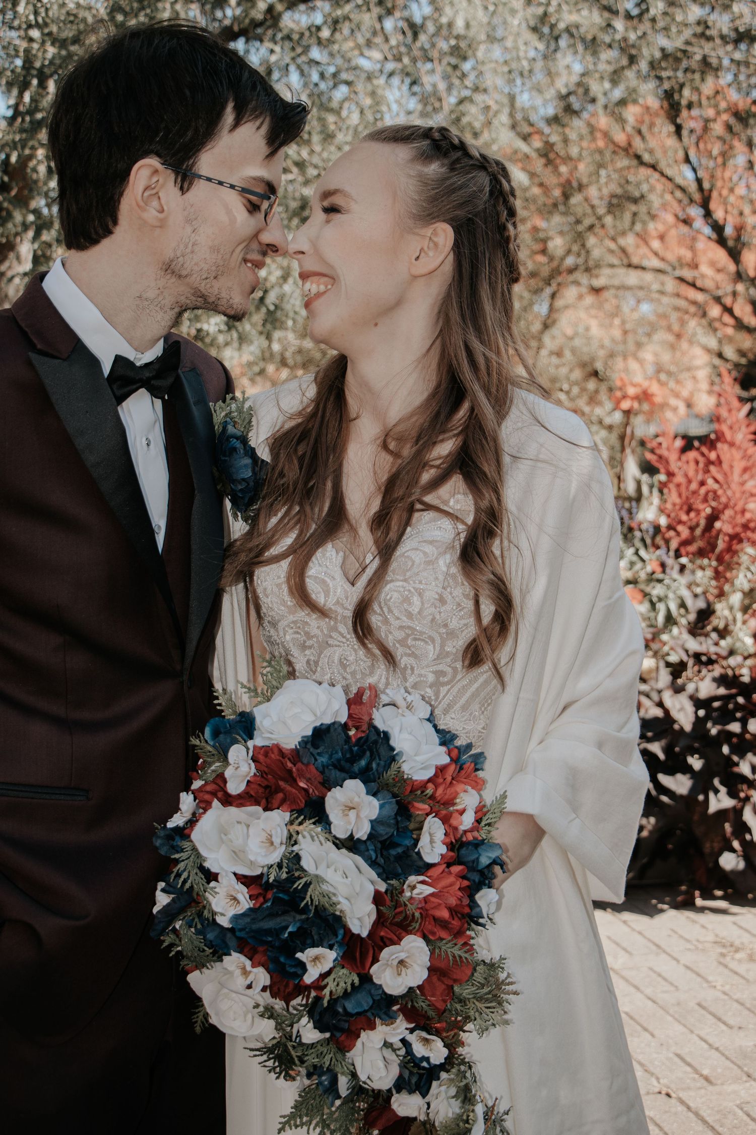 Romantic winter wedding photos with red and blue bouquet against a backdrop of cherry blossoms.