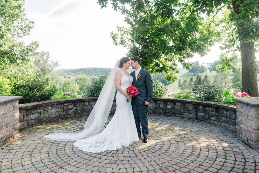 Romantic wedding portrait on a circular stone patio surrounded by lush greenery.