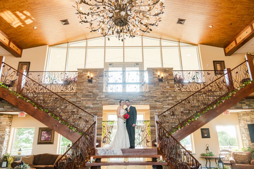 A stunning wedding venue interior features dual staircases and a dramatic crystal chandelier.
