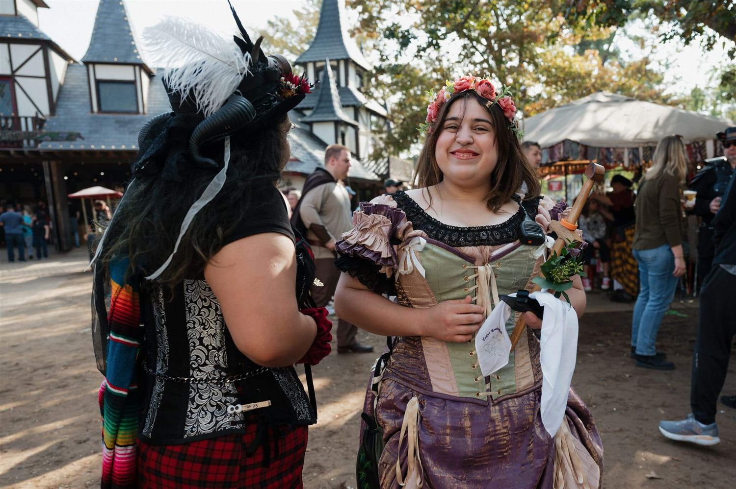 Costumed performers in Renaissance attire interact at an outdoor festival.