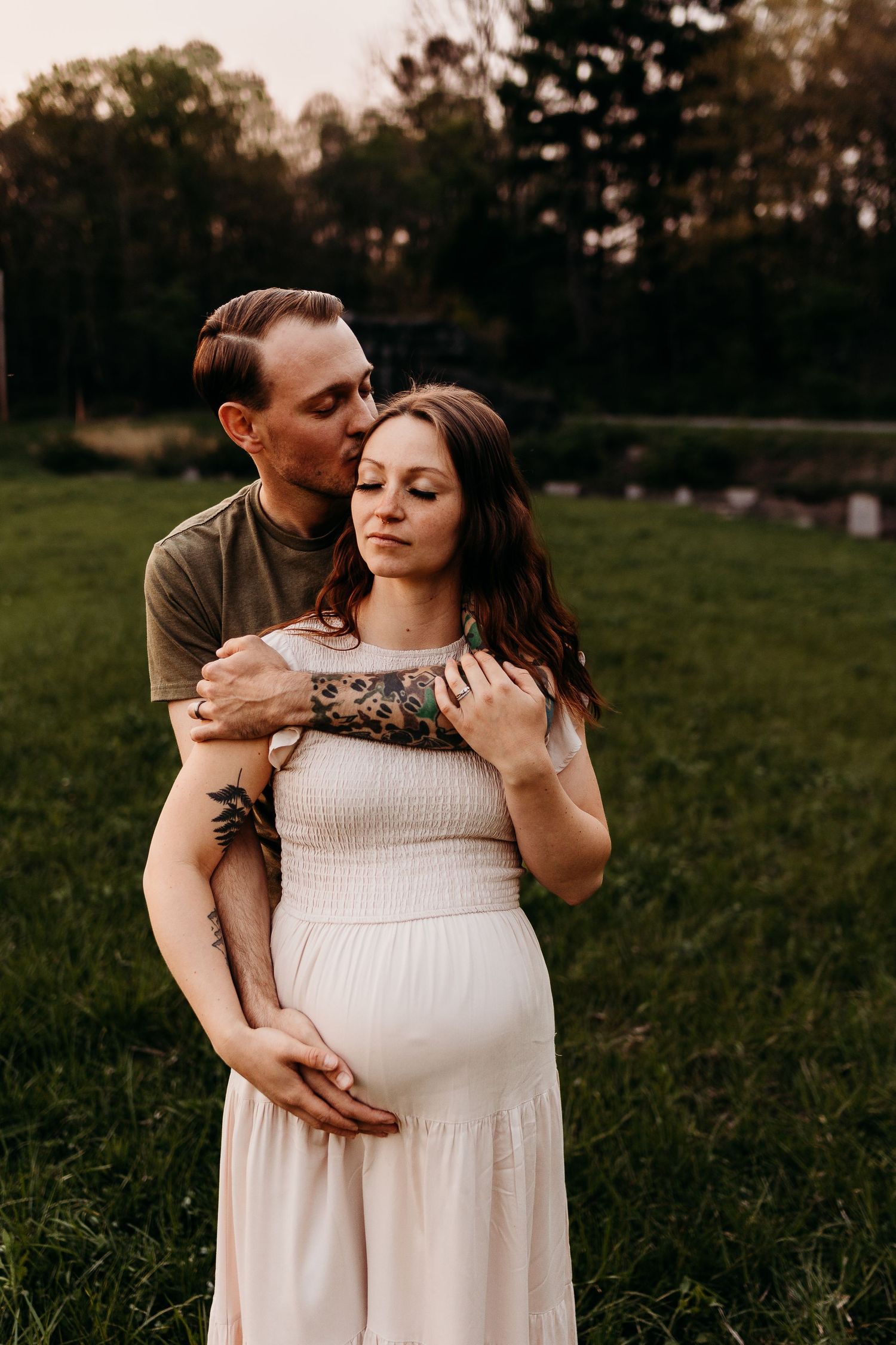 Tender maternity portrait of couple embracing in golden evening light.