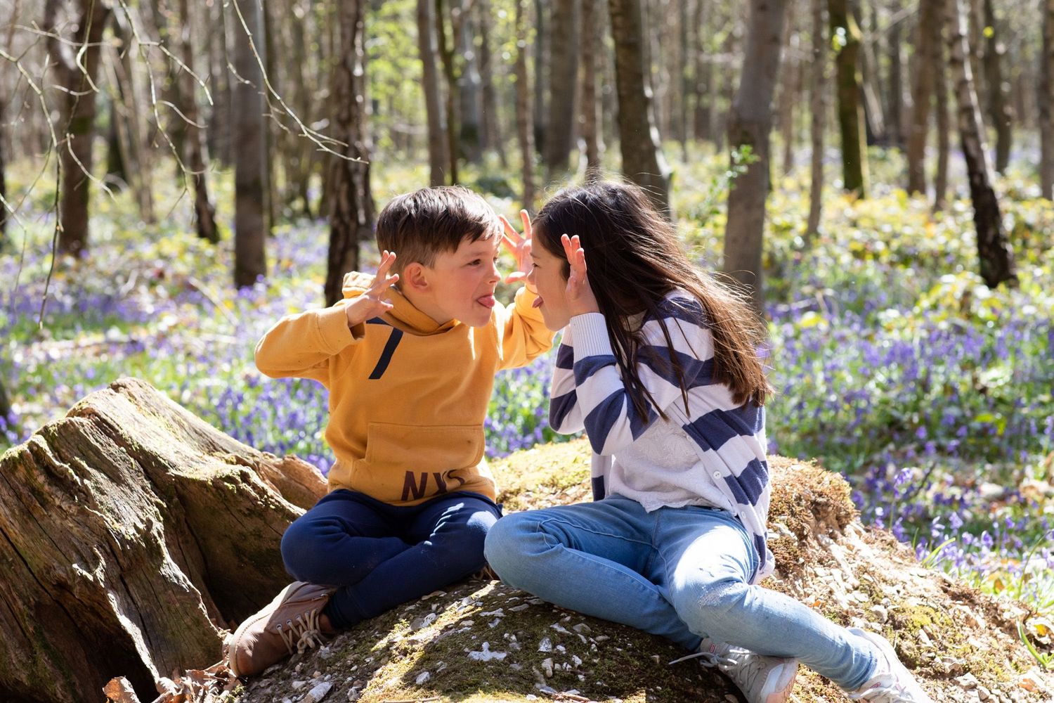 Two people sharing a playful moment in a woodland filled with bluebells.