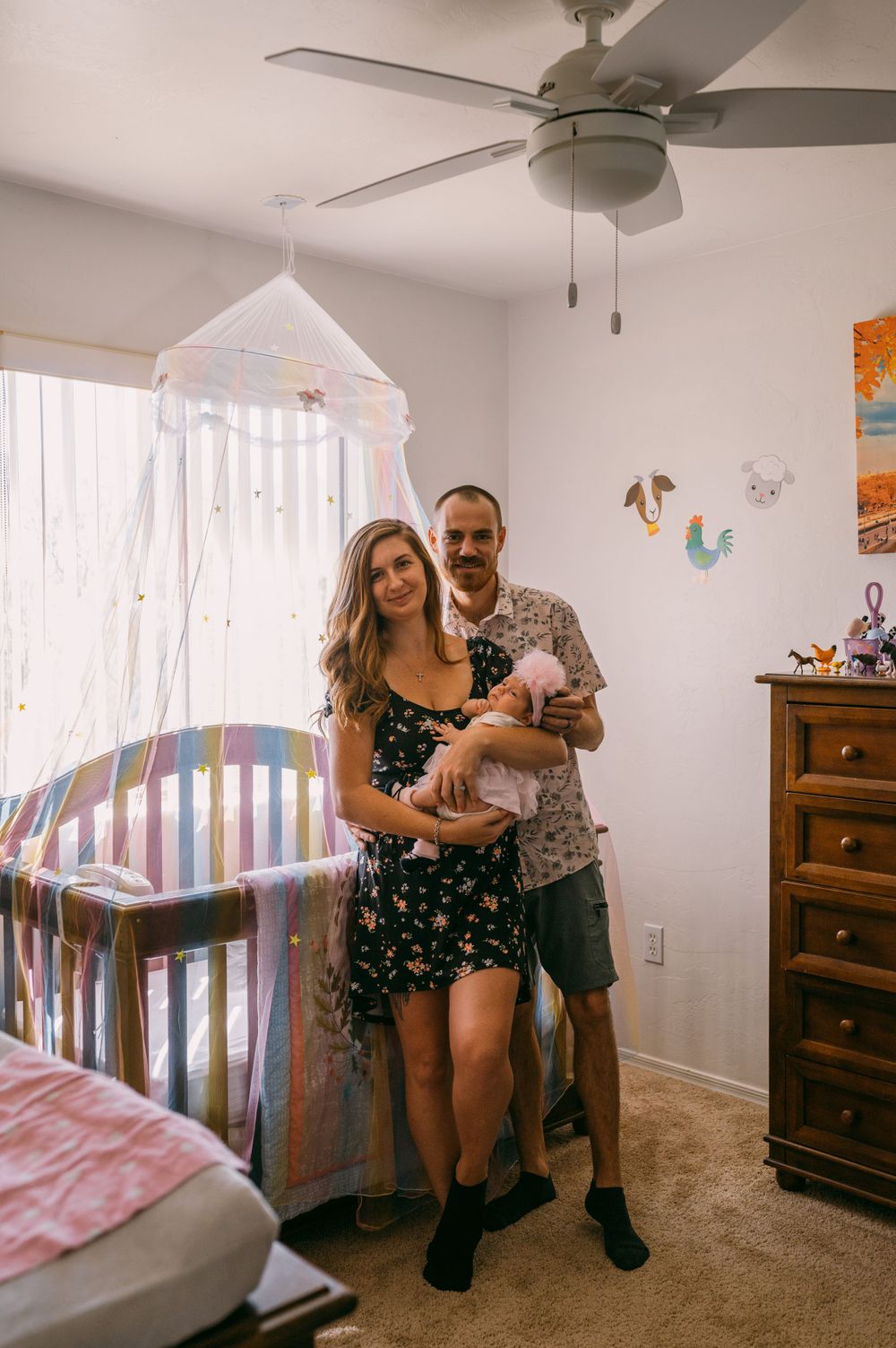 Couple exploring a nursery room with white walls and wooden furniture.