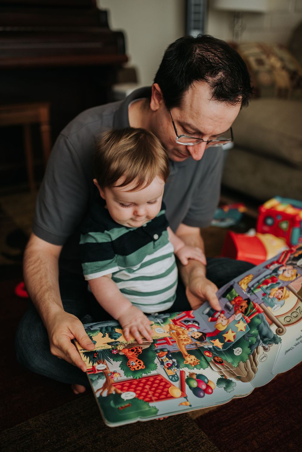 Parent and child reading a colorful storybook together on a dark wooden table.