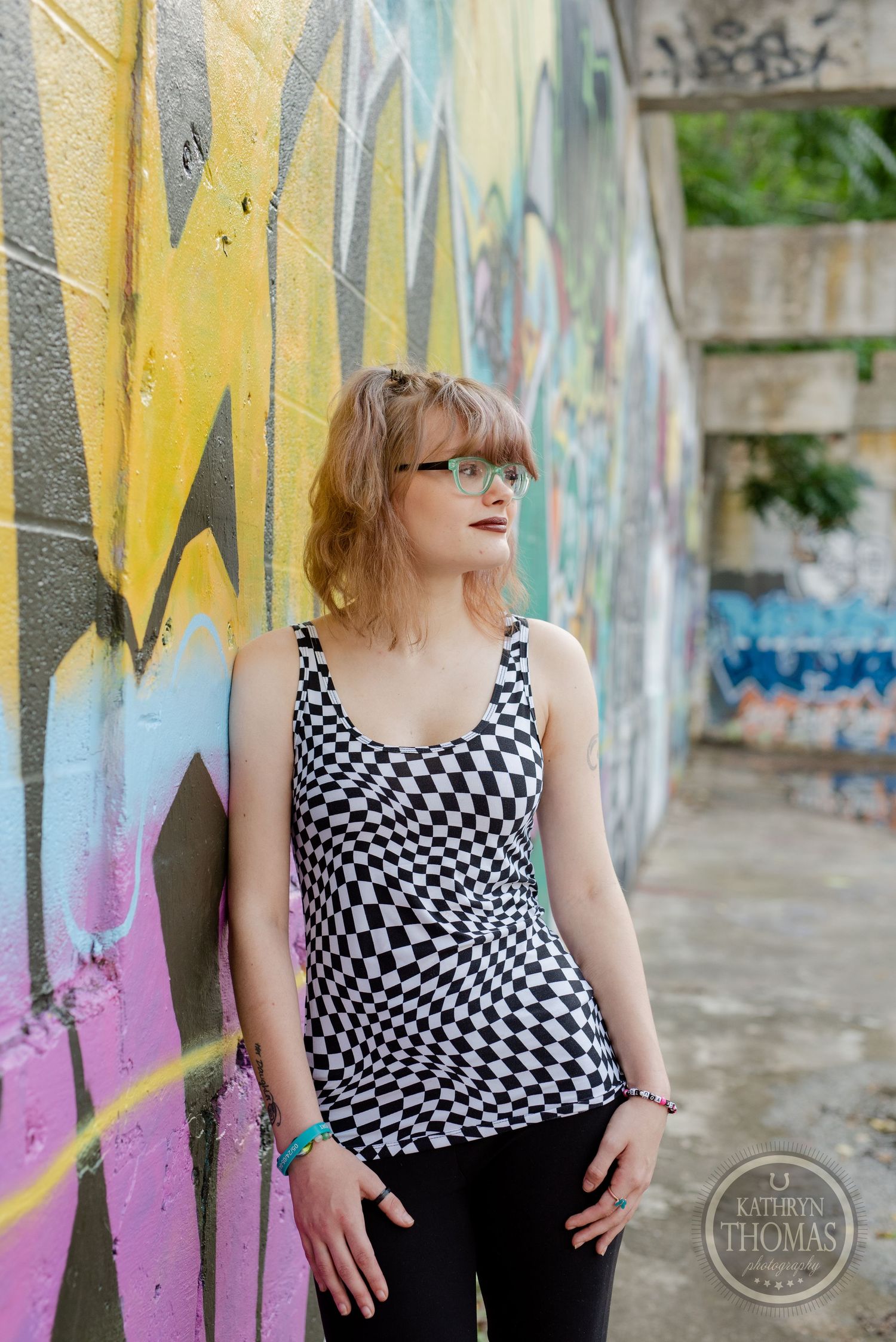 A styled portrait against colorful graffiti wearing geometric print top and dark pants.