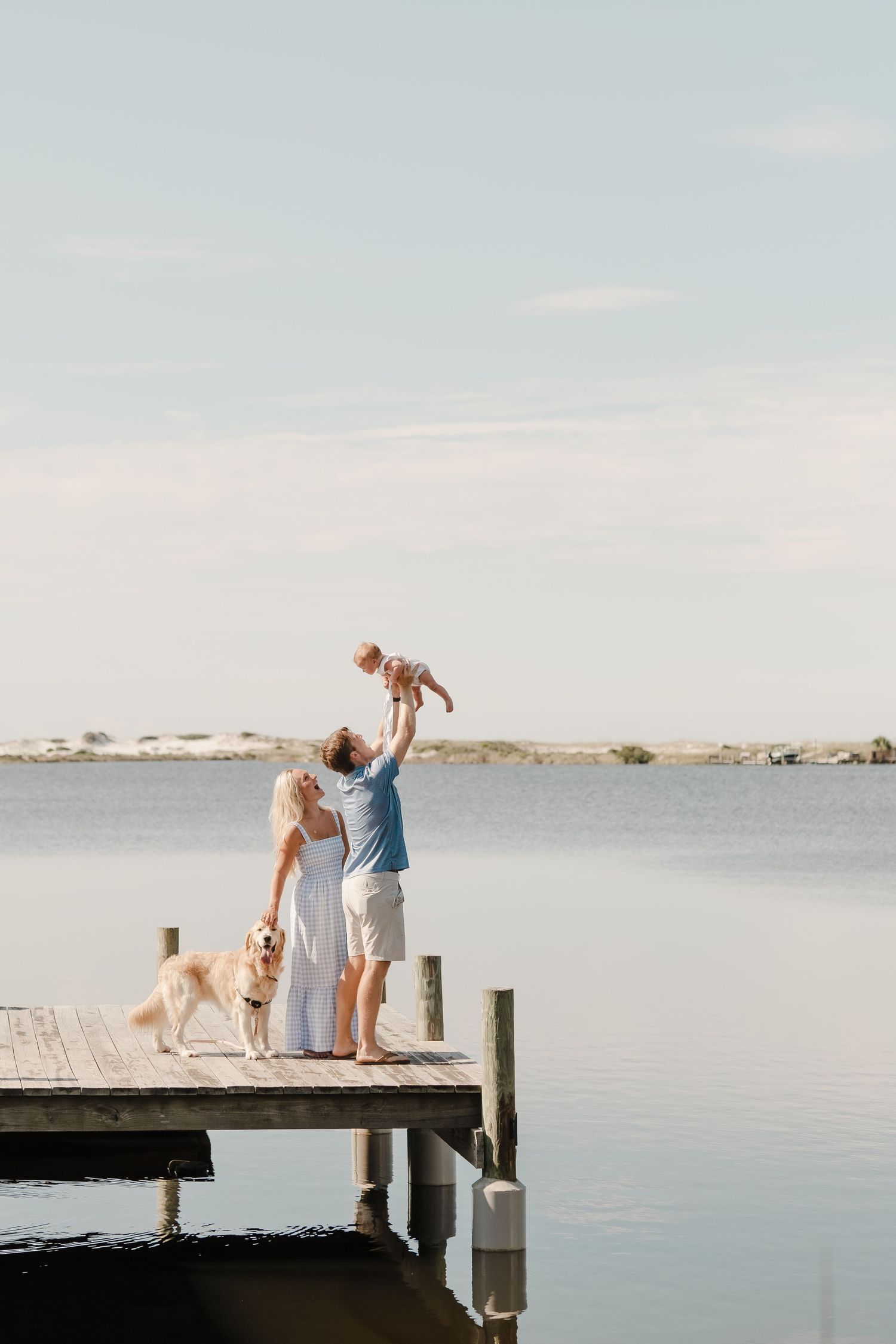 Family enjoying a peaceful moment together on a wooden pier overlooking calm waters.