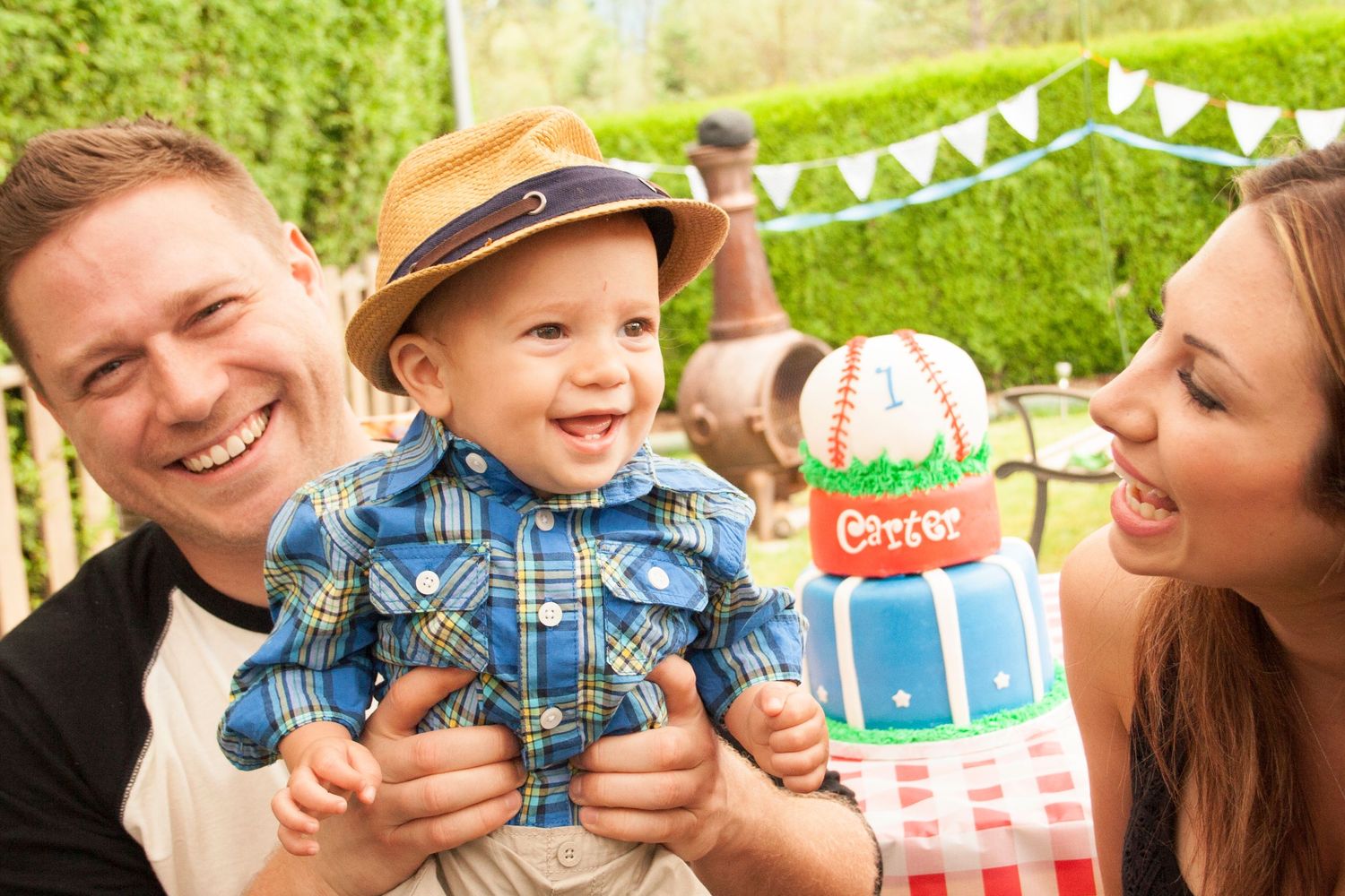Family celebrating with cake at outdoor first birthday party.