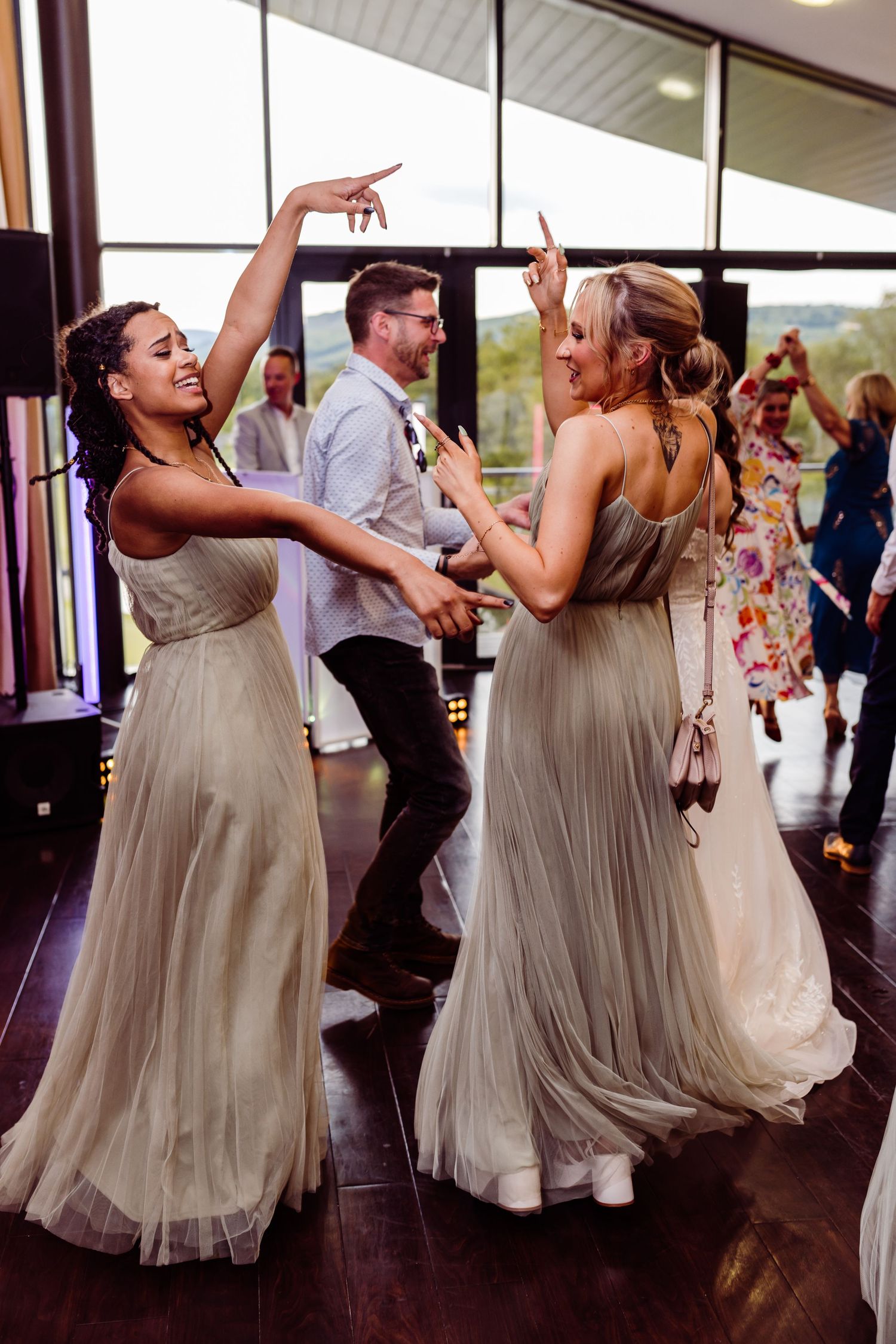 Wedding guests in formal attire dancing together at an indoor reception venue.