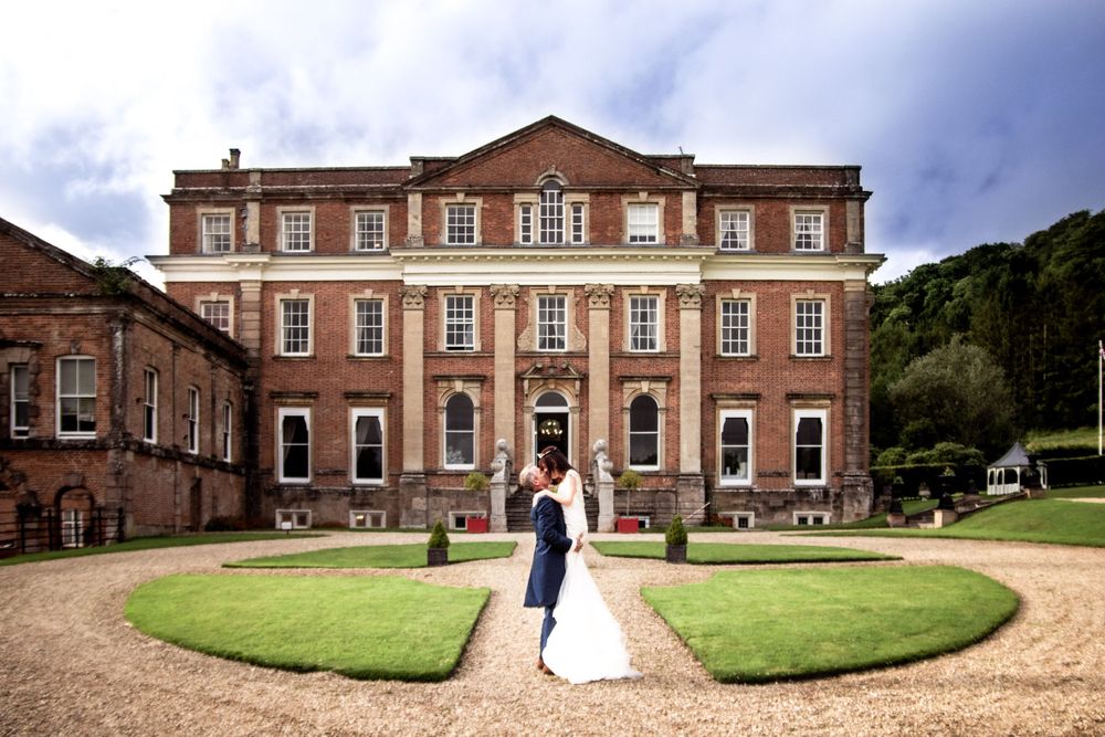 Stately Georgian mansion with manicured circular lawn and newlyweds in foreground.